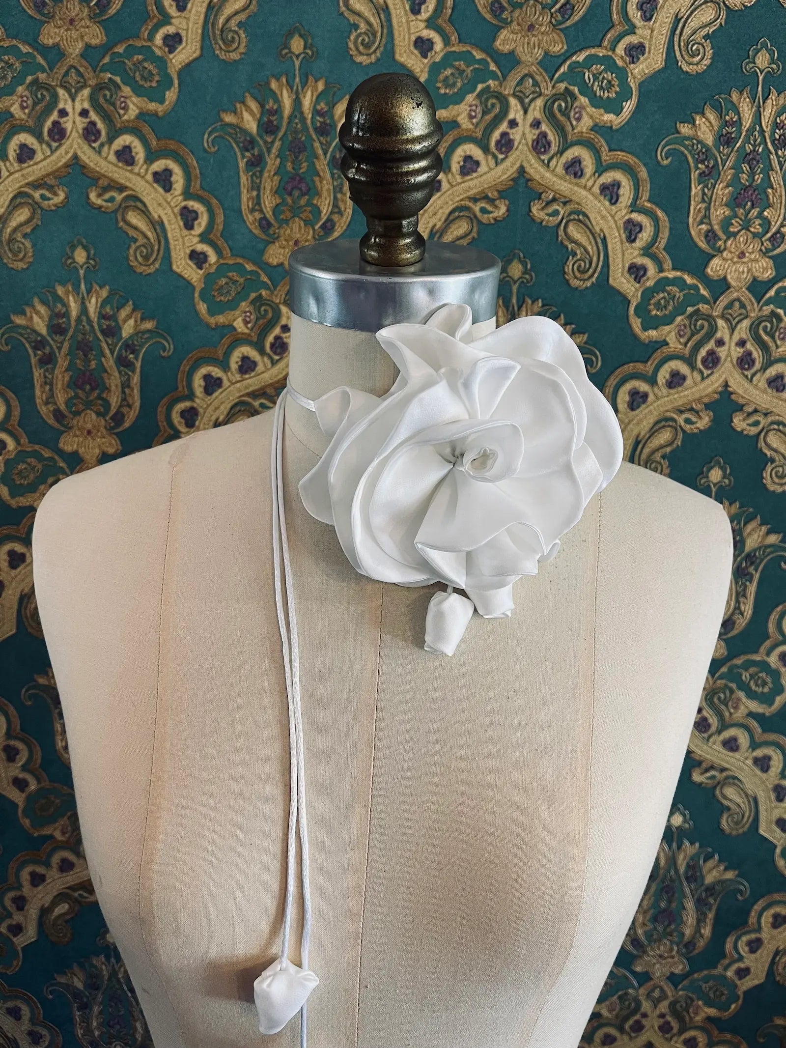 Broochella Rosetta white handmade silk satin flower brooch and choker  Pictured on a mannequin. The background is green and gold damask wallpaper