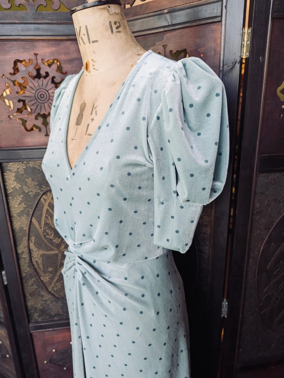 Rotate By Birger Christensen Green Velvet Polka Dot Midi Dress- UK 10. It is pictured on a mannequin. The background is an ornate dark wood room divider. 