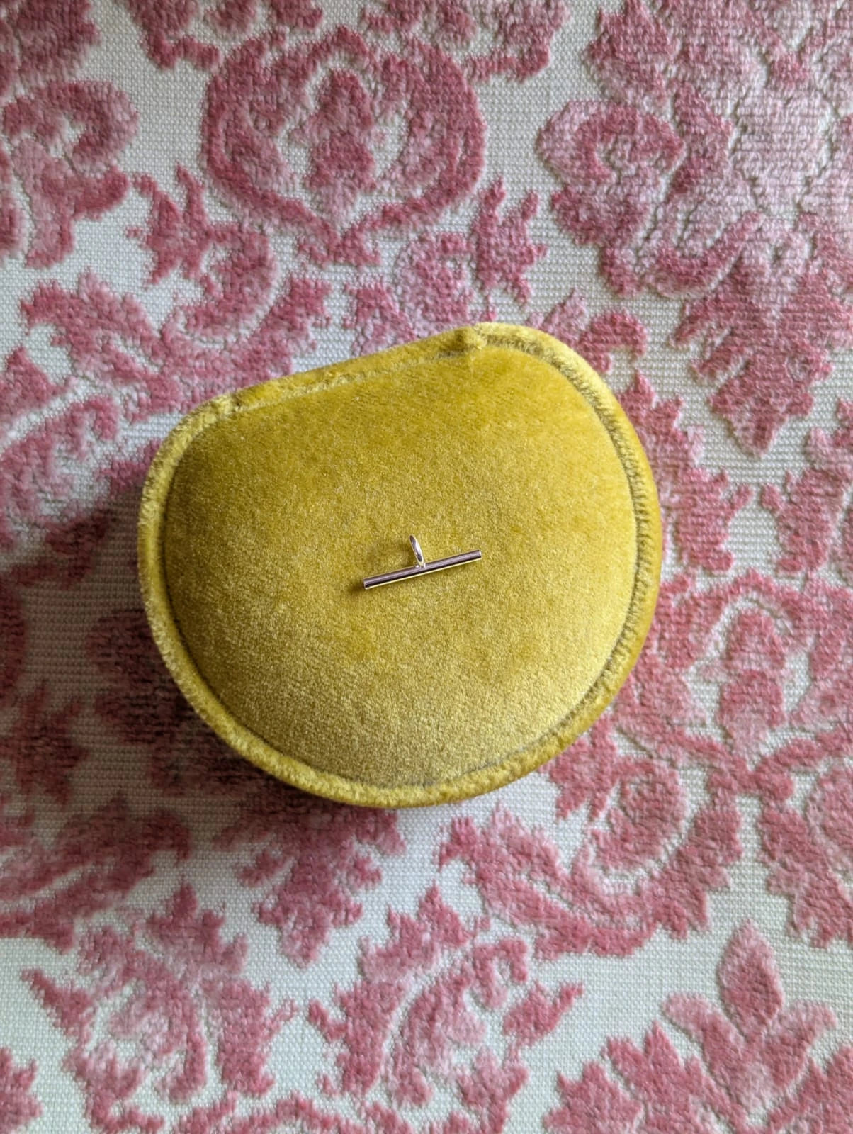 Broochella silver brooch to necklace brooch converter- extended bar. Pictured on a chartreuse ring box. The background is pale pink damask fabric.