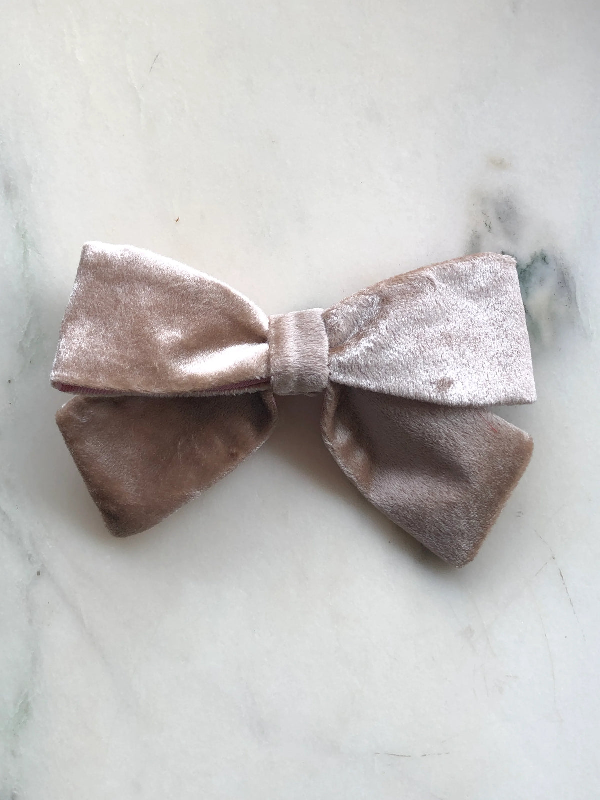 Broochella handmade Small Velvet Bow Brooch in luxurious champagne velvet with contrasting pink lining, featuring a designer double bow with softly structured loops, photographed on white marble.