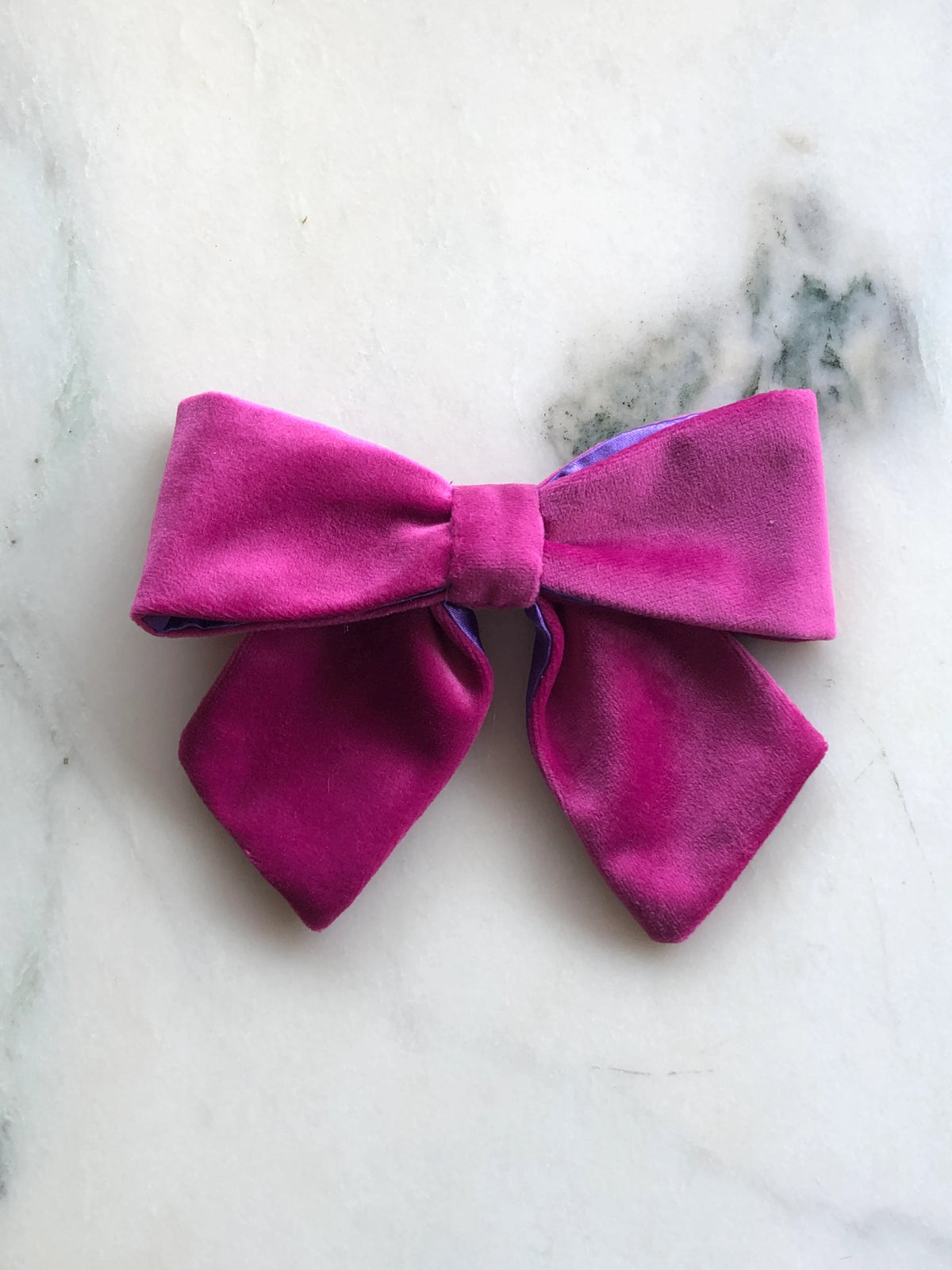 Broochella handmade Small Velvet Bow Brooch in rich magenta velvet with contrasting purple edging, featuring a designer double bow with softly structured loops, photographed on white marble.