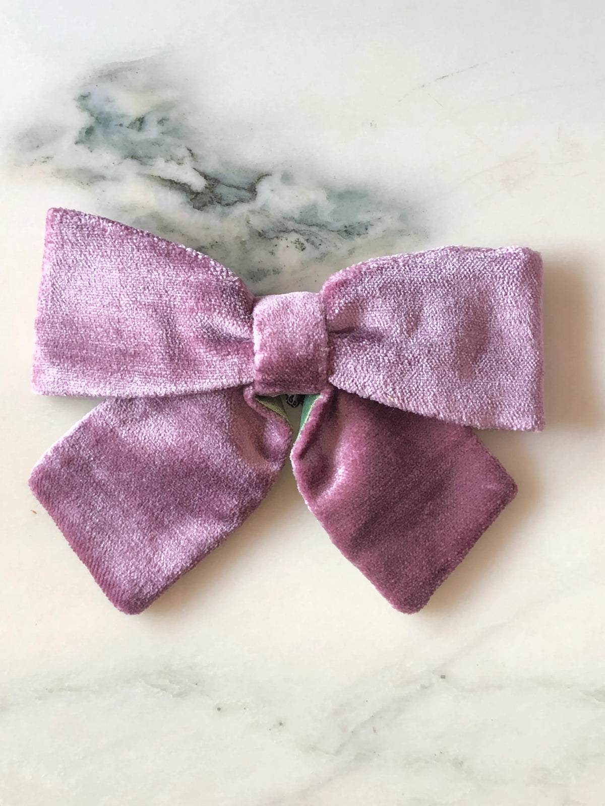 Broochella men's handmade Small Velvet Bow Brooch in soft violet velvet with contrasting green lining, featuring a designer double bow with softly structured loops, photographed on white marble.