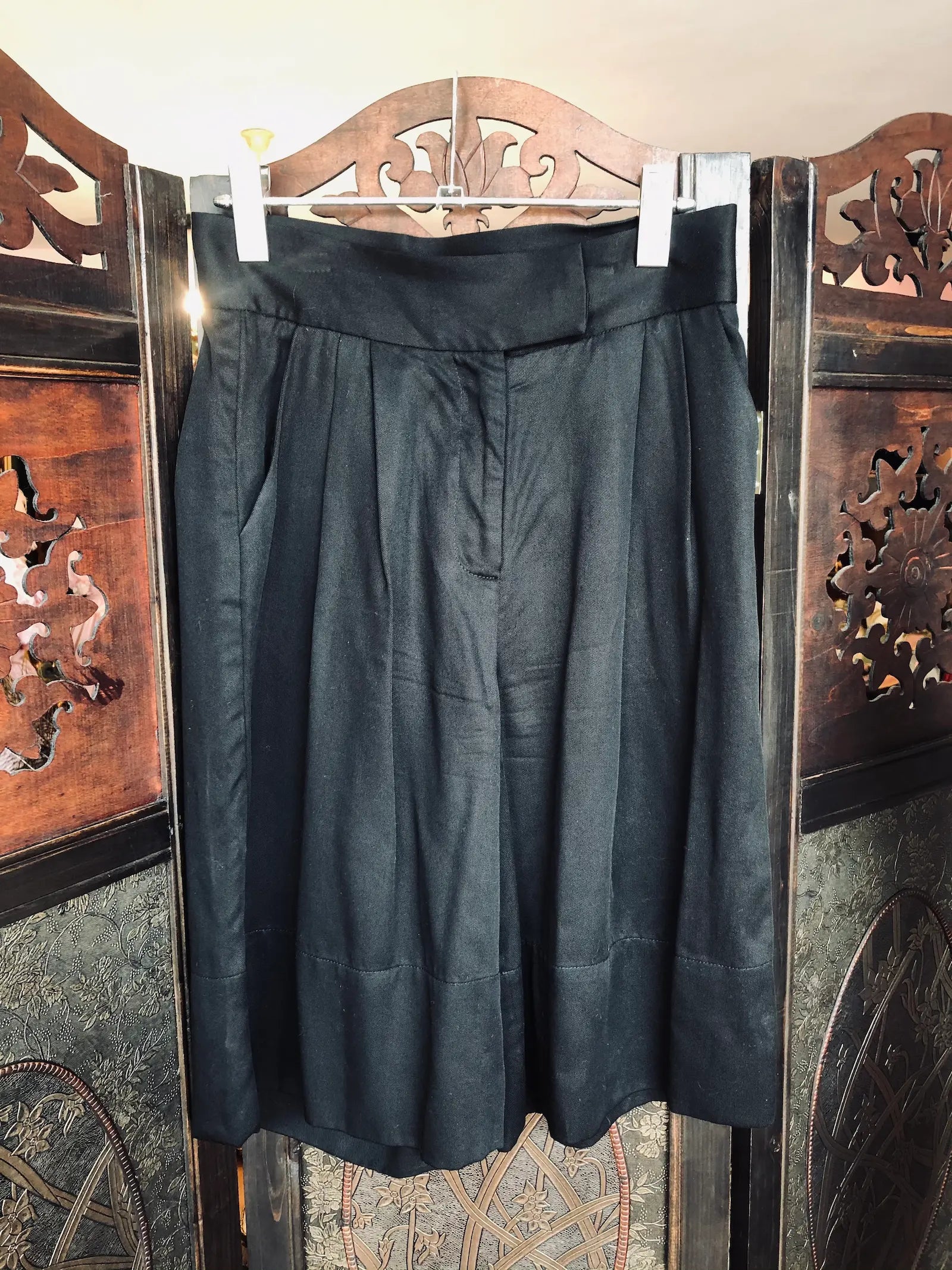 Broochella The Stylist's Closet St Agni black, tailored, lyocell shorts. They are hanging from an ornate, vintage, dark wood room divider. 