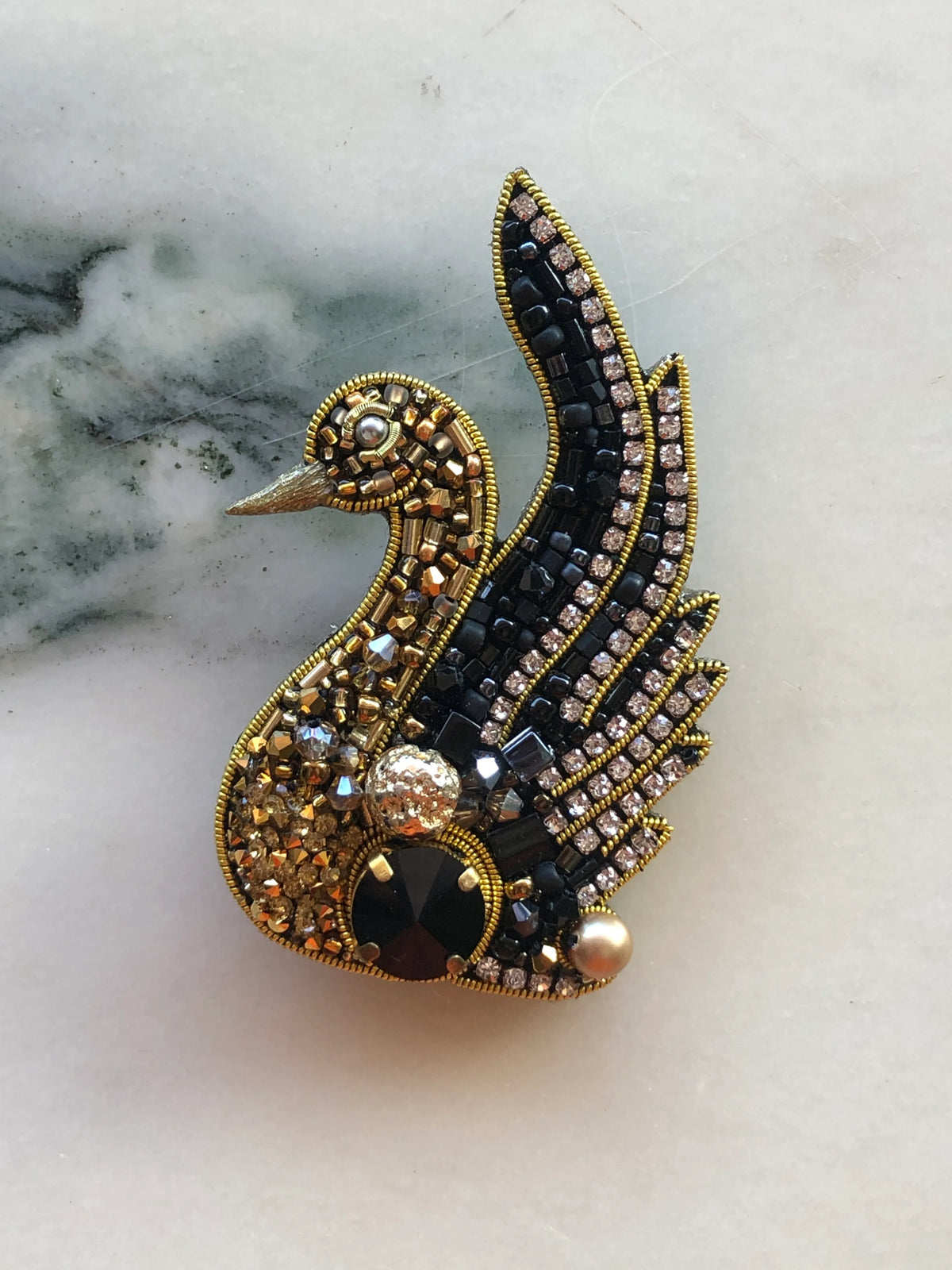 Broochella Swan Hand-Beaded Brooch Pin featuring intricate black and gold beadwork, sparkling crystals, pearls and dimensional embellishments.