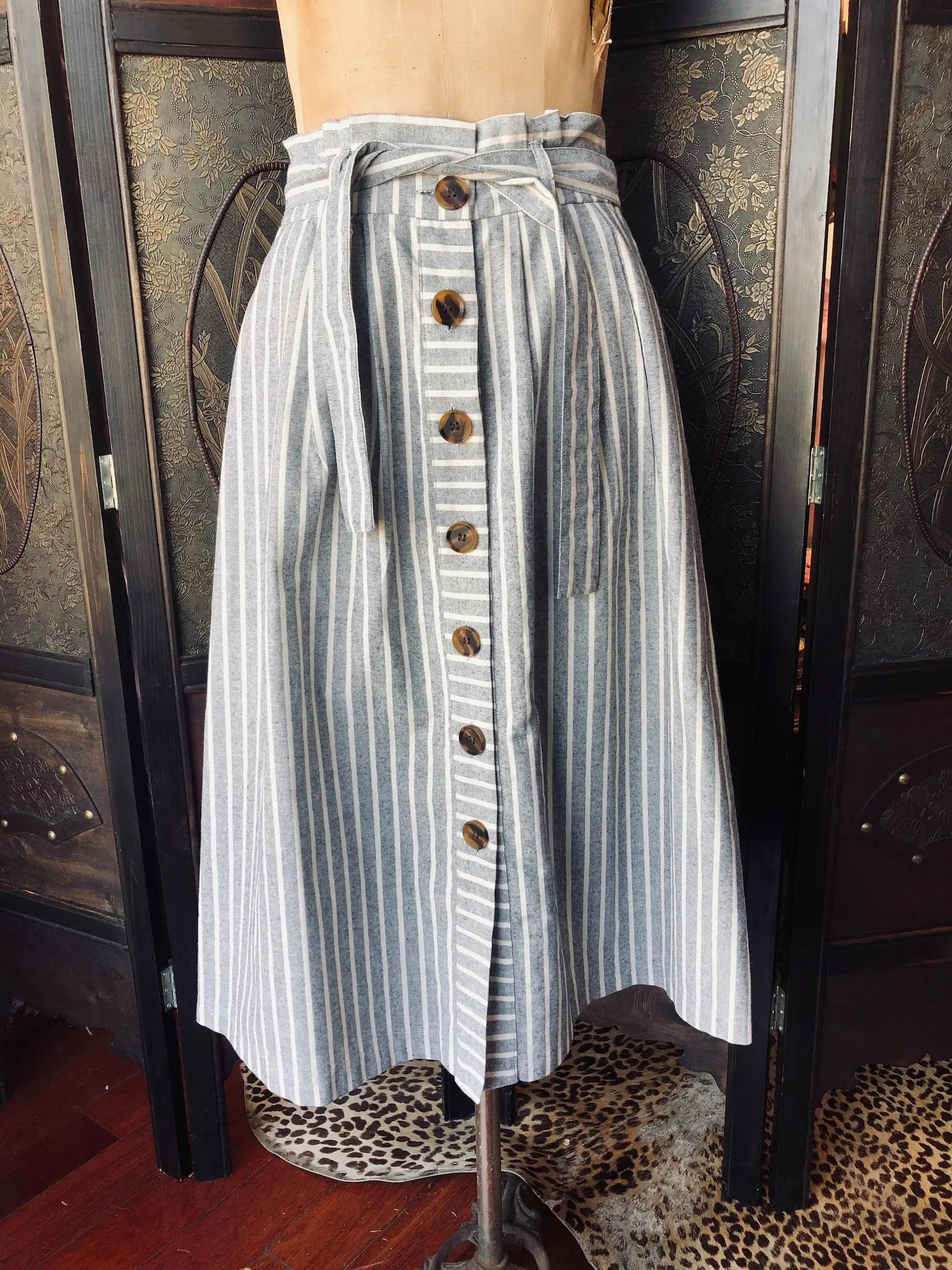 Broochella Topshop Striped button-up blue and white striped cotton skirt on a mannequin against a decorative wall.