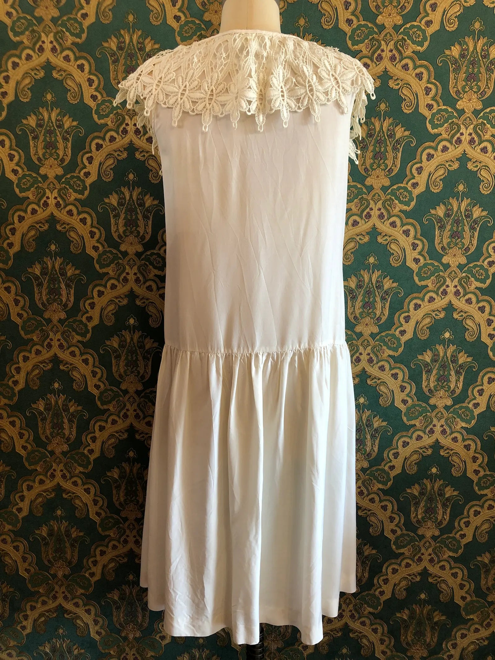 Broochella vintage Ninette ivory silk maxi dress with an ornate lace cape collar, deep V-neckline and satin bow, labelled vintage AU 12 and approximately modern AU 8. Pictured on a mannequin against green and gold damask wallpaper.