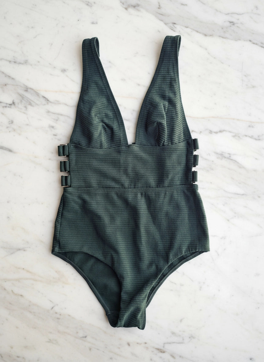 Broochella Zimmerman size 10 one piece swimsuit in green. It is pictured on a white marble surface. 