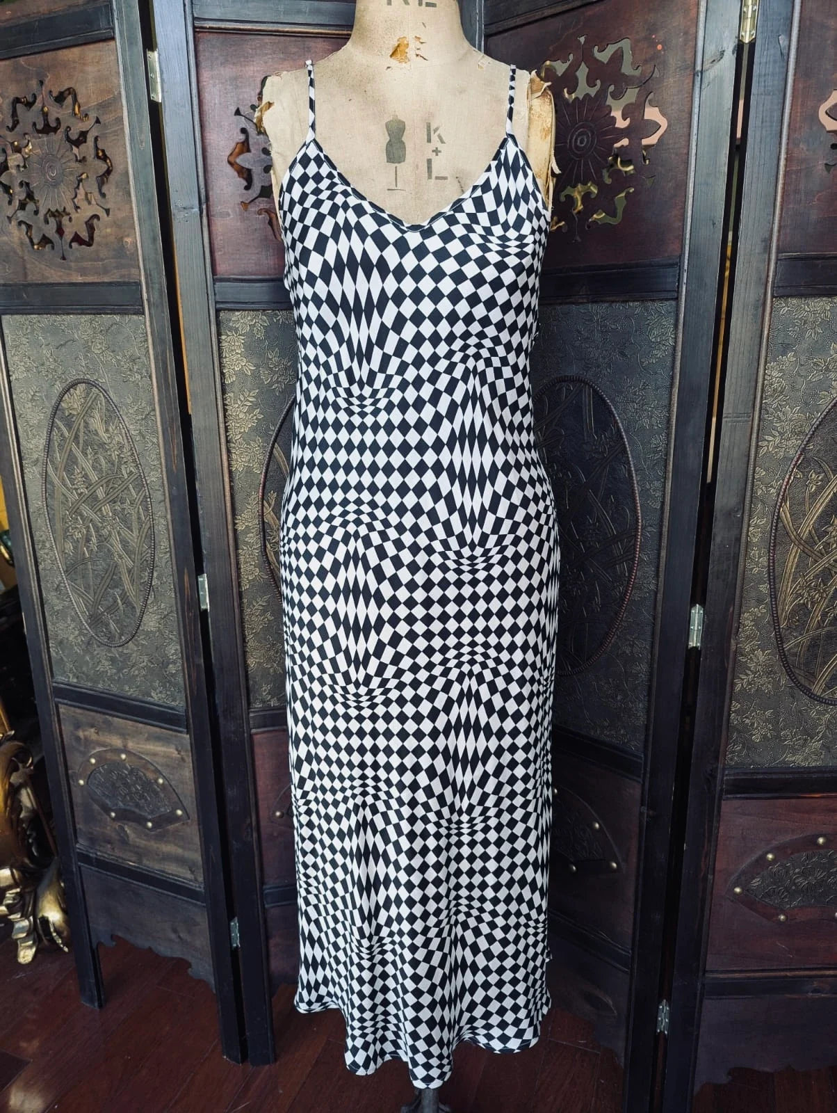 Broochella Silk Laundry Op Art Check Slip Dress – Size S.  Pictured on a mannequin. The background is an ornate dark wood room divider. 